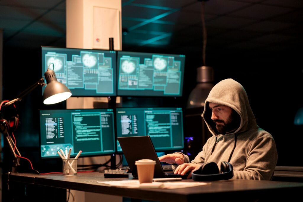 A security analyst working at a bank of monitors in a darkened operations room
