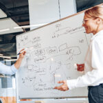 Two colleagues working through a data model sketched on a whiteboard