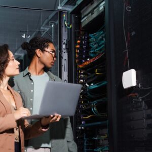 An engineer walking a data centre aisle between server racks