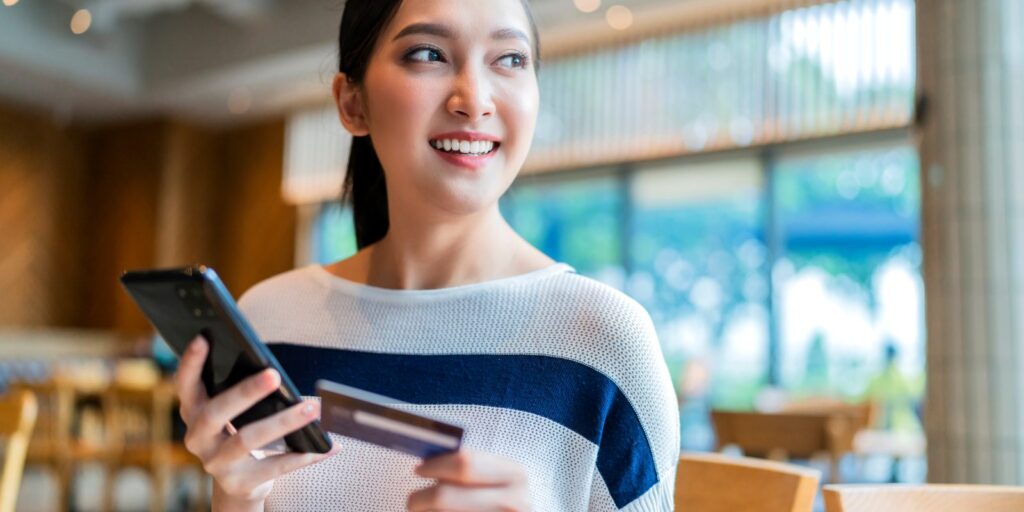 A customer holding a bank card and a phone while paying