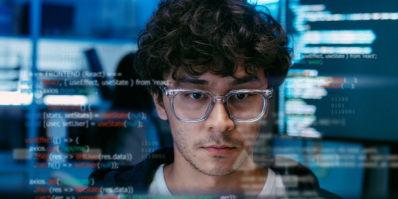 Developer coding on screen with code overlay, representing deepfake hiring fraud detection.